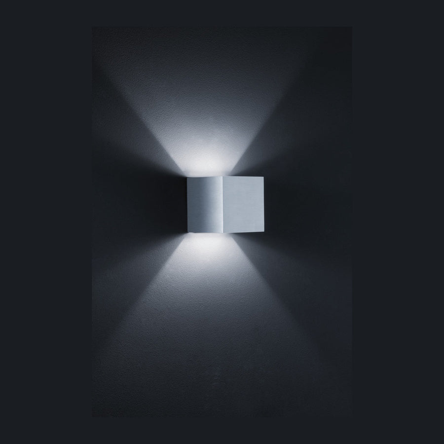 Applique carrée en aluminium gris diffusant deux faisceaux lumineux verticaux sur un mur sombre