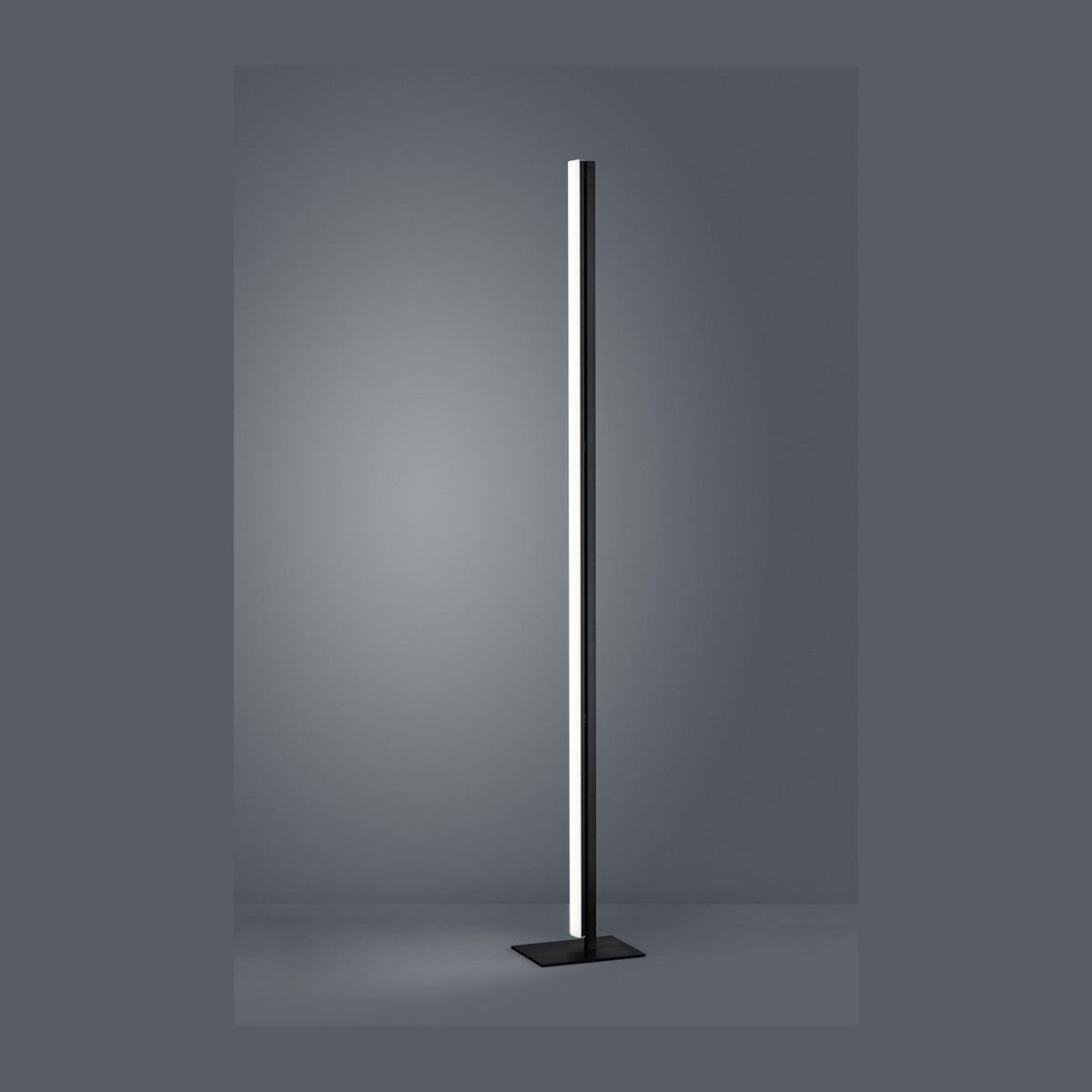 Lampadaire colonne noir très fin, vu de face sur fond gris neutre, socle plat carré.