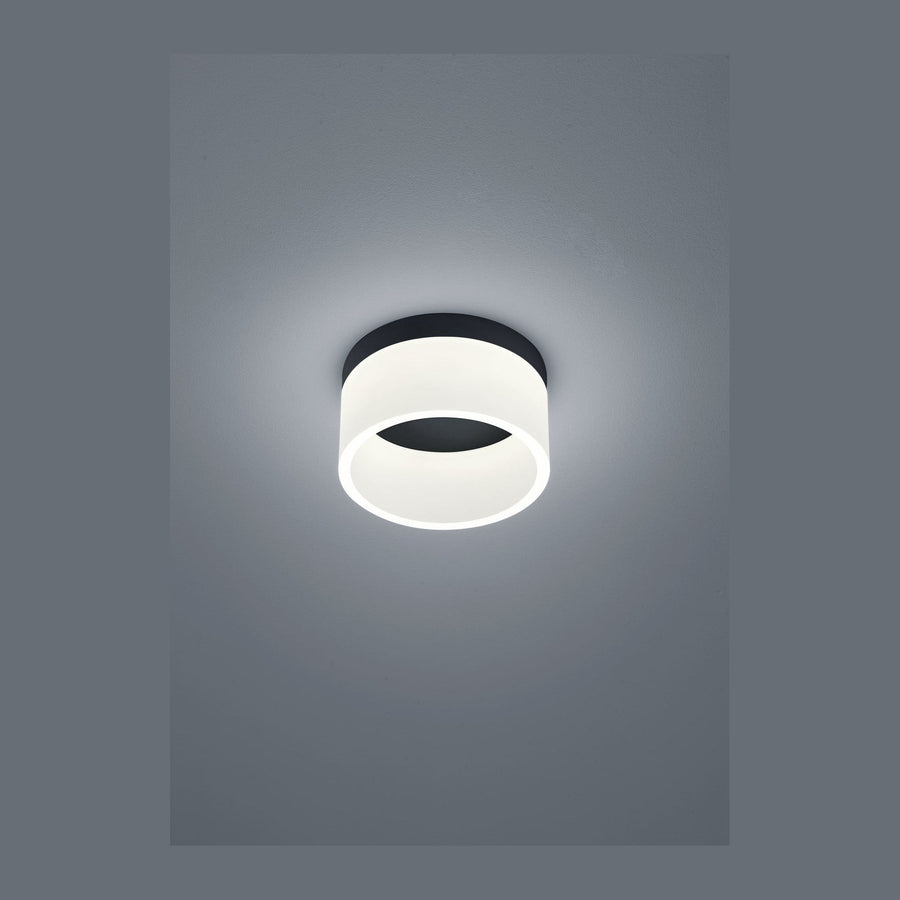 Plafonnier noir et blanc allumé fixé au plafond, vu de face.