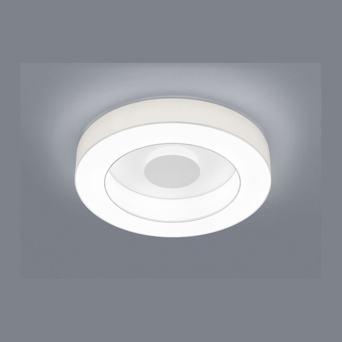 Plafonnier rond blanc vu de face, anneaux lumineux concentriques et bord en tissu
