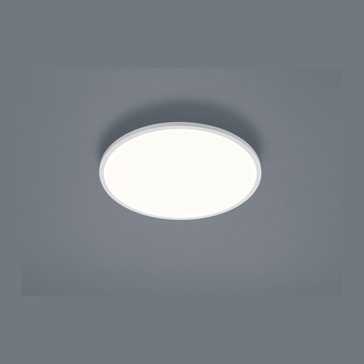 Plafonnier rond blanc fixé au plafond, vue de face sur fond gris