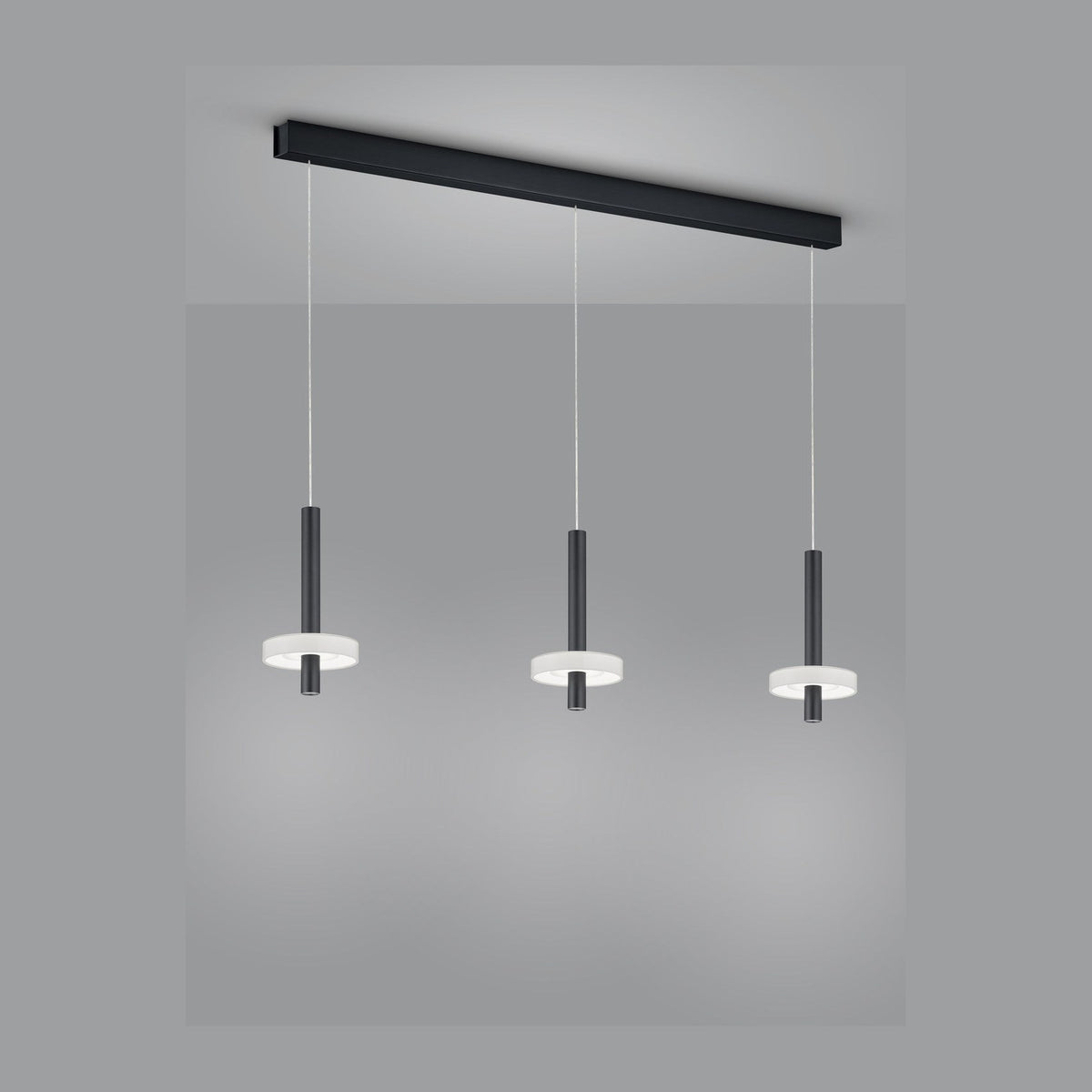 Suspension noire à trois pendants cylindriques sous une longue barre rectangulaire fixée au plafond.
