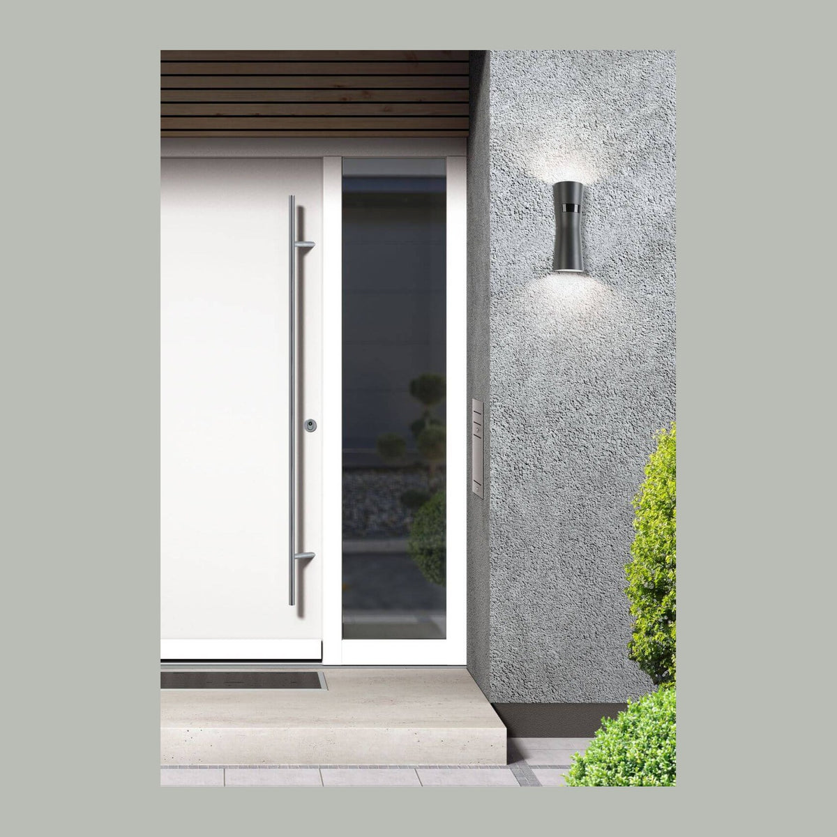 Applique extérieure anthracite allumée sur mur gris, près d'une porte d'entrée blanche