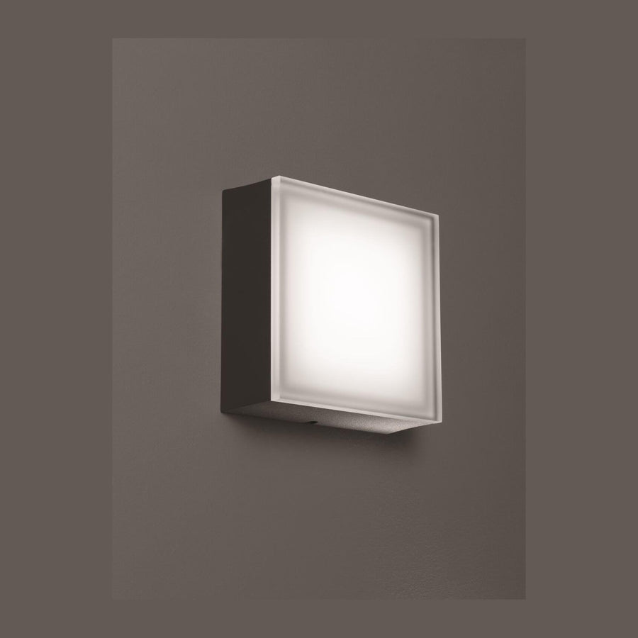 Vue de trois quarts du luminaire allumé sur fond gris foncé uniforme
