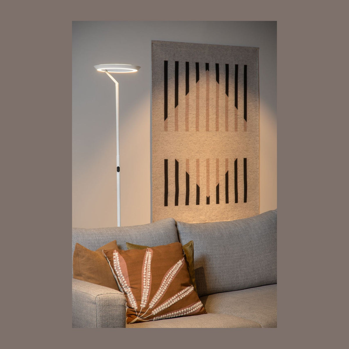 Mise en ambiance du lampadaire allumé près d'un canapé gris dans un salon