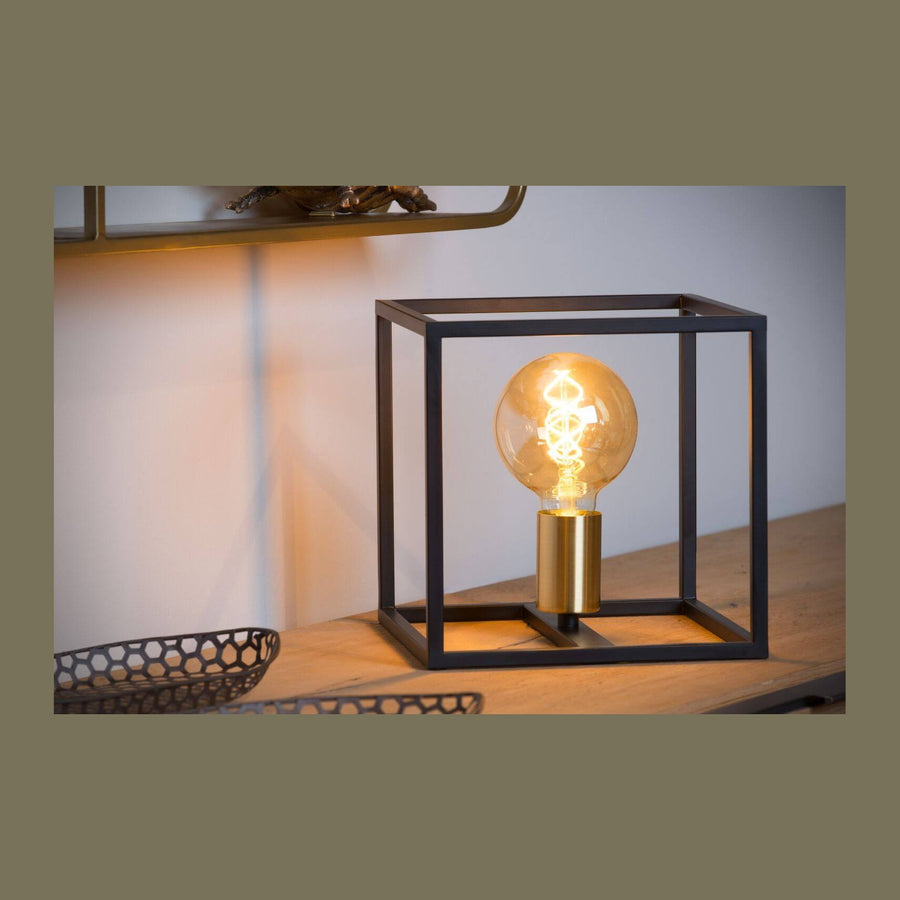 Lampe posée sur table en bois, ampoule allumée dans cadre noir carré