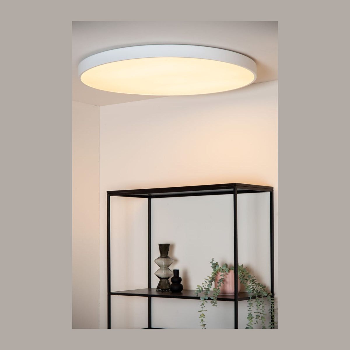 Plafonnier rond blanc allumé fixé au plafond dans un intérieur épuré