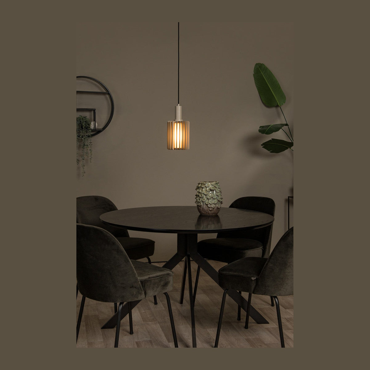 Suspension allumée au-dessus d'une table ronde noire entourée de chaises en velours