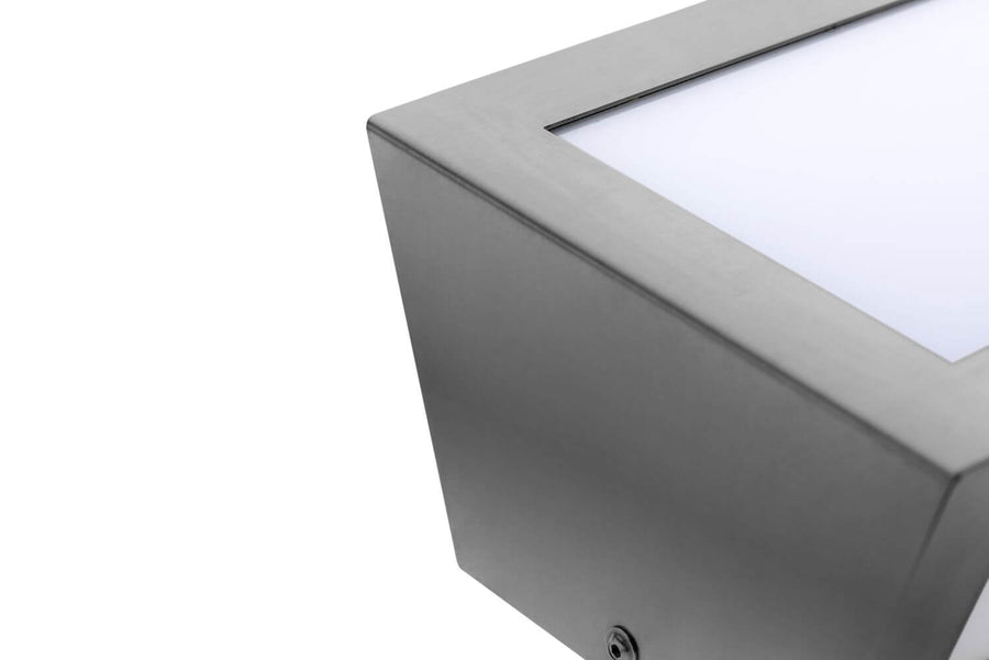 Détail du coin supérieur en inox brossé et du panneau diffusant blanc.
