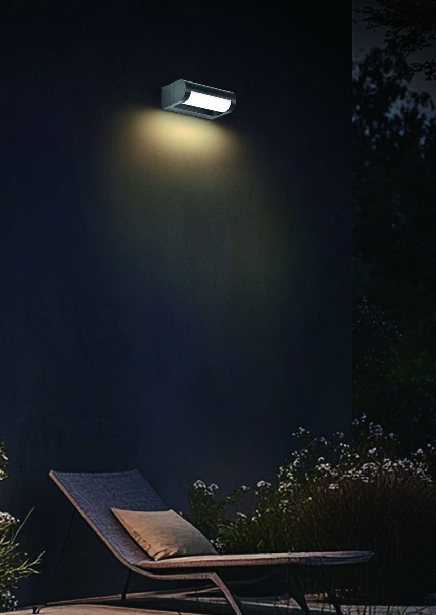Mise en ambiance nocturne, applique allumée éclairant un mur près d'une chaise longue