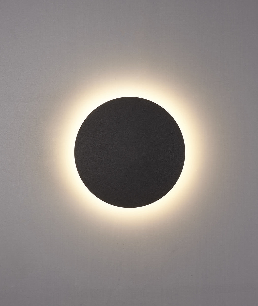 Applique allumée de face projetant un halo lumineux chaud sur le mur