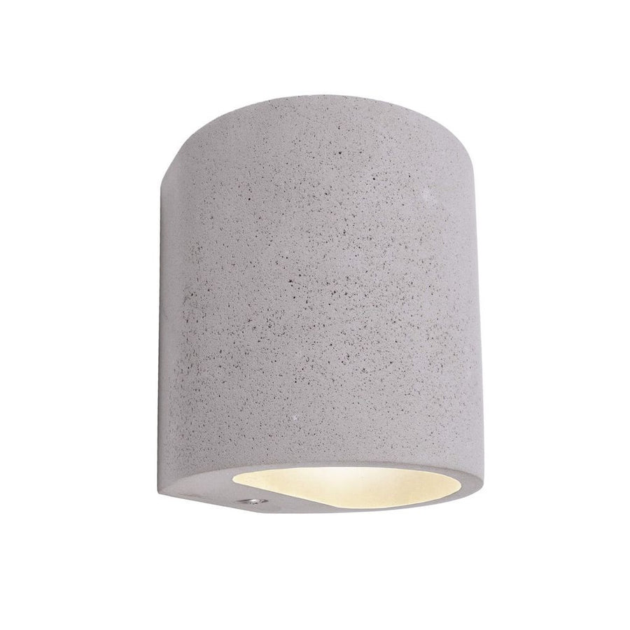 Applique murale en béton gris, forme cylindrique bombée, éclairage doux vers le bas sur fond blanc.