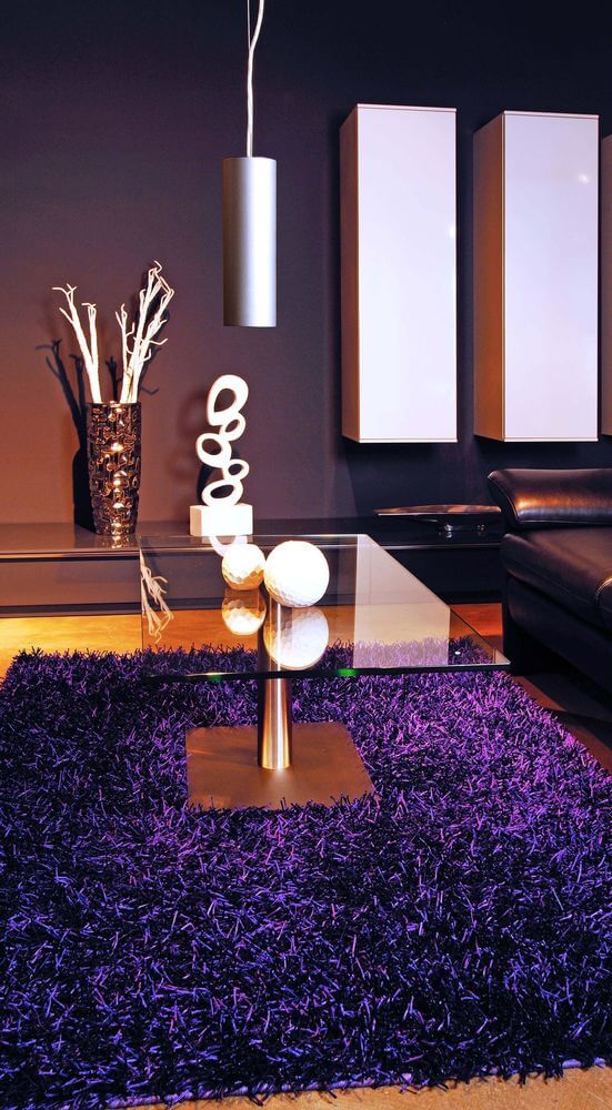 Mise en ambiance dans un salon sombre avec la suspension allumée au-dessus de la table.