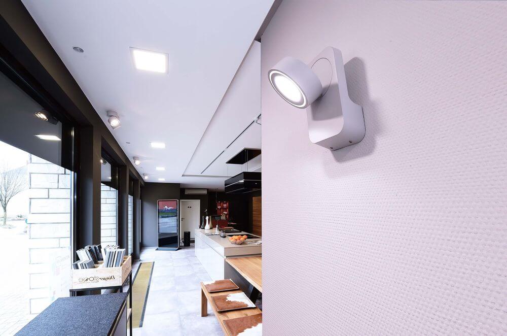 Spot mural blanc installé dans un couloir de cuisine moderne et lumineux.