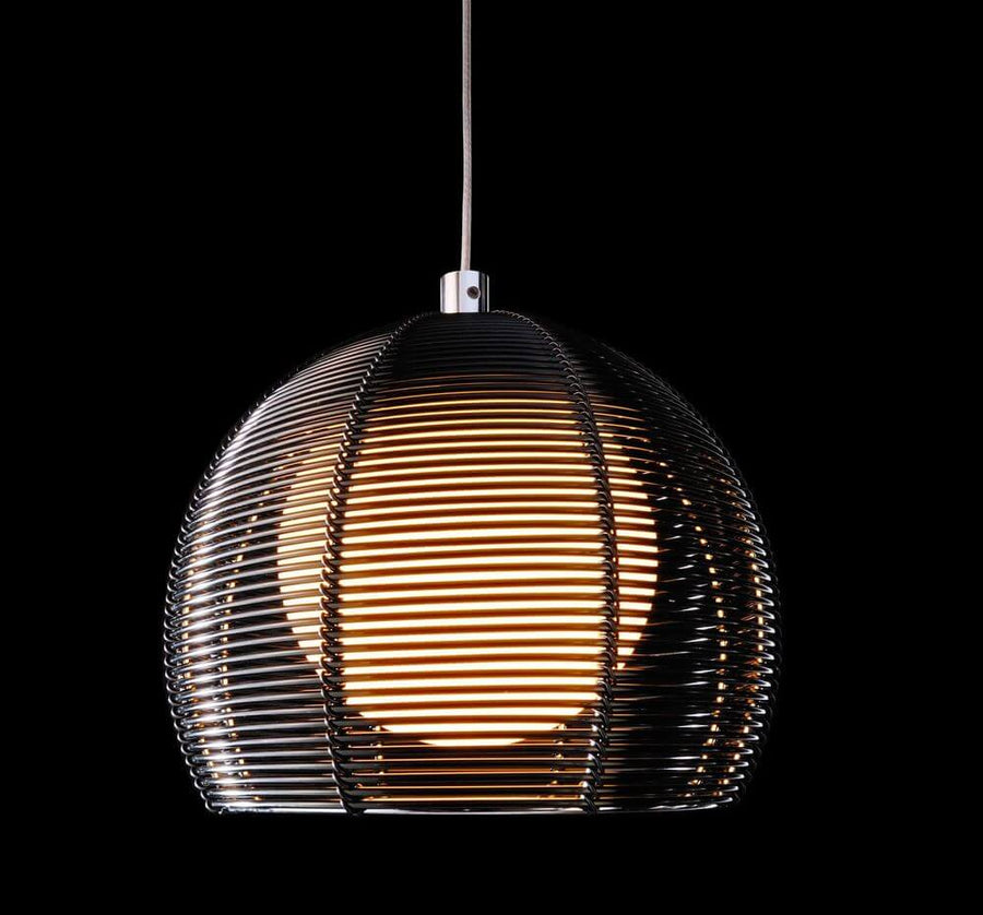 Même suspension allumée sur fond noir, lumière chaude traversant la grille.
