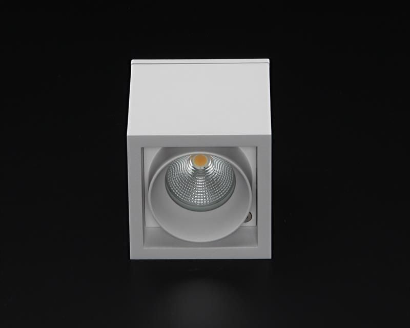 Vue de face sur fond noir, projecteur LED orientable et réflecteur strié visible.