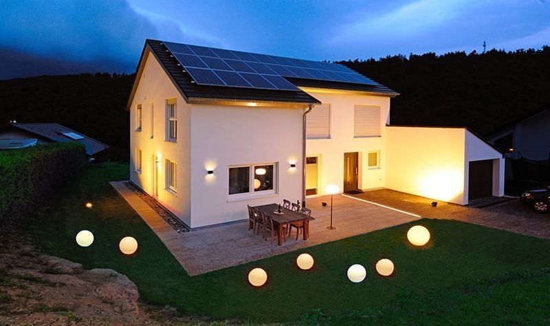 Maison de nuit avec plusieurs lampes sphériques lumineuses disposées sur la pelouse