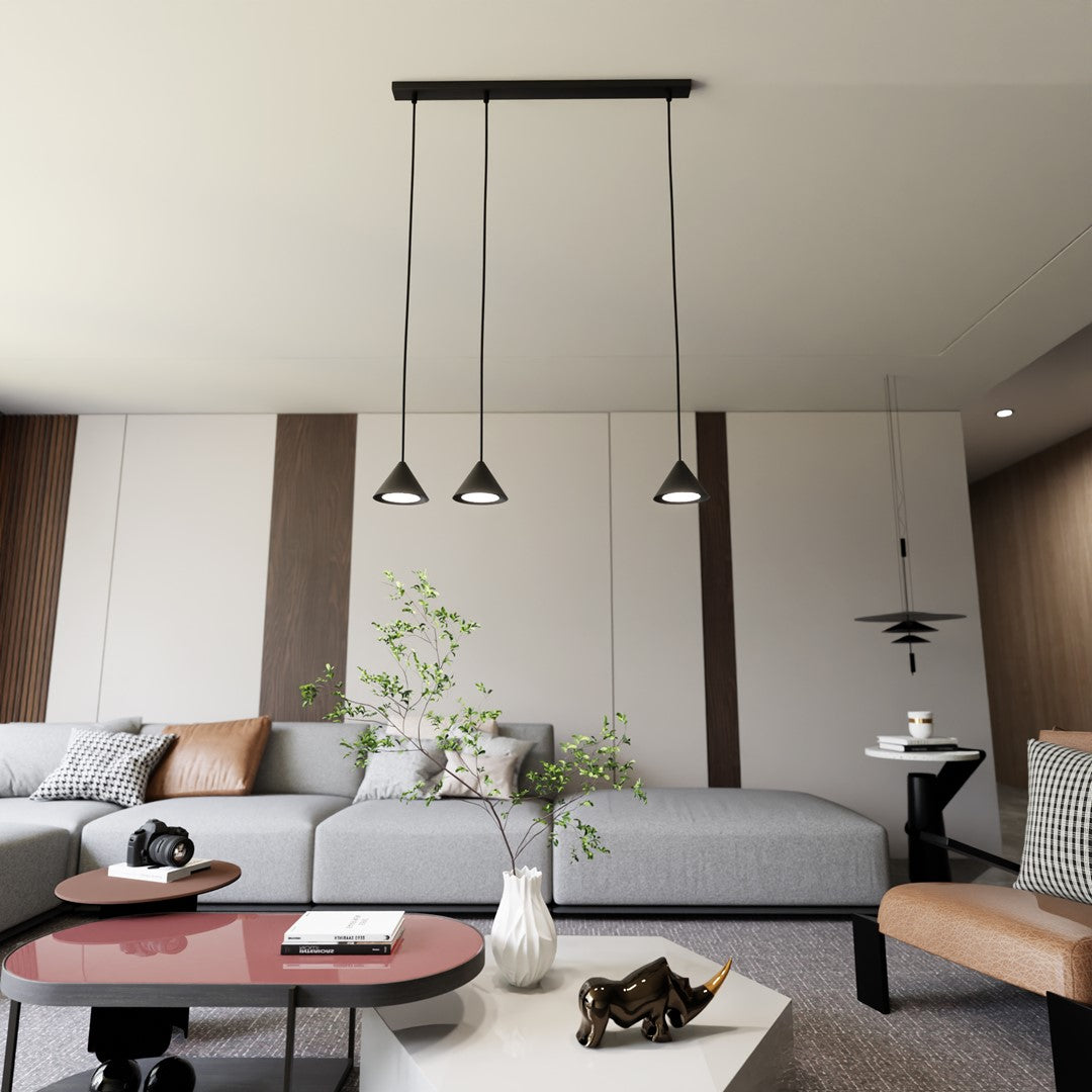 Suspension noire installée au-dessus d’un canapé gris dans un salon moderne clair.