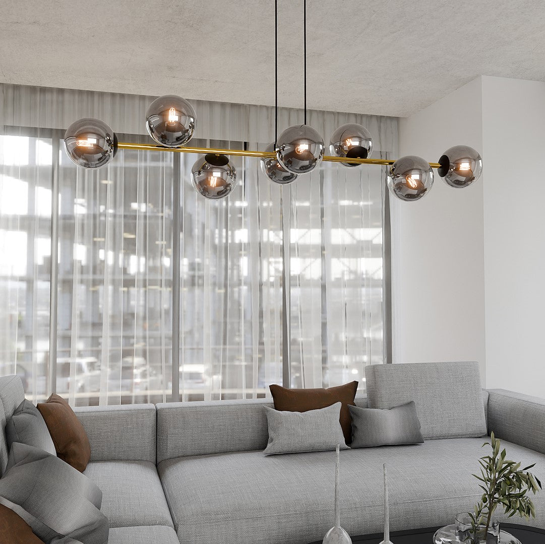 Mise en ambiance salon clair, suspension allumée au-dessus d’un canapé gris et rideaux voilés.