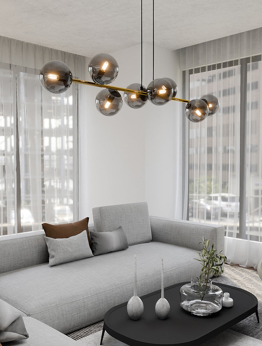 Vue rapprochée du luminaire allumé dans le salon, canapé, coussins et table basse noire.