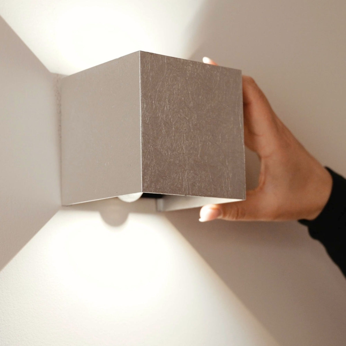 Main tenant l'applique cube, détail de la finition métal brossé gris