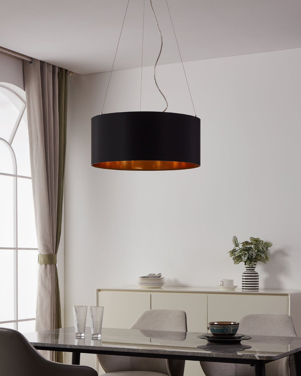 Suspension noire et dorée installée au-dessus d'une table de salle à manger