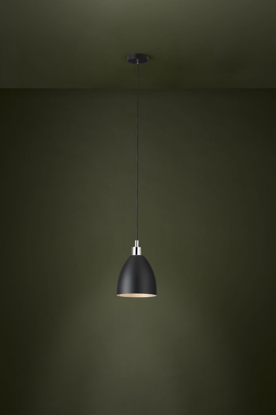 Luminaire suspendu allumé dans une pièce sombre vert olive, lumière chaude