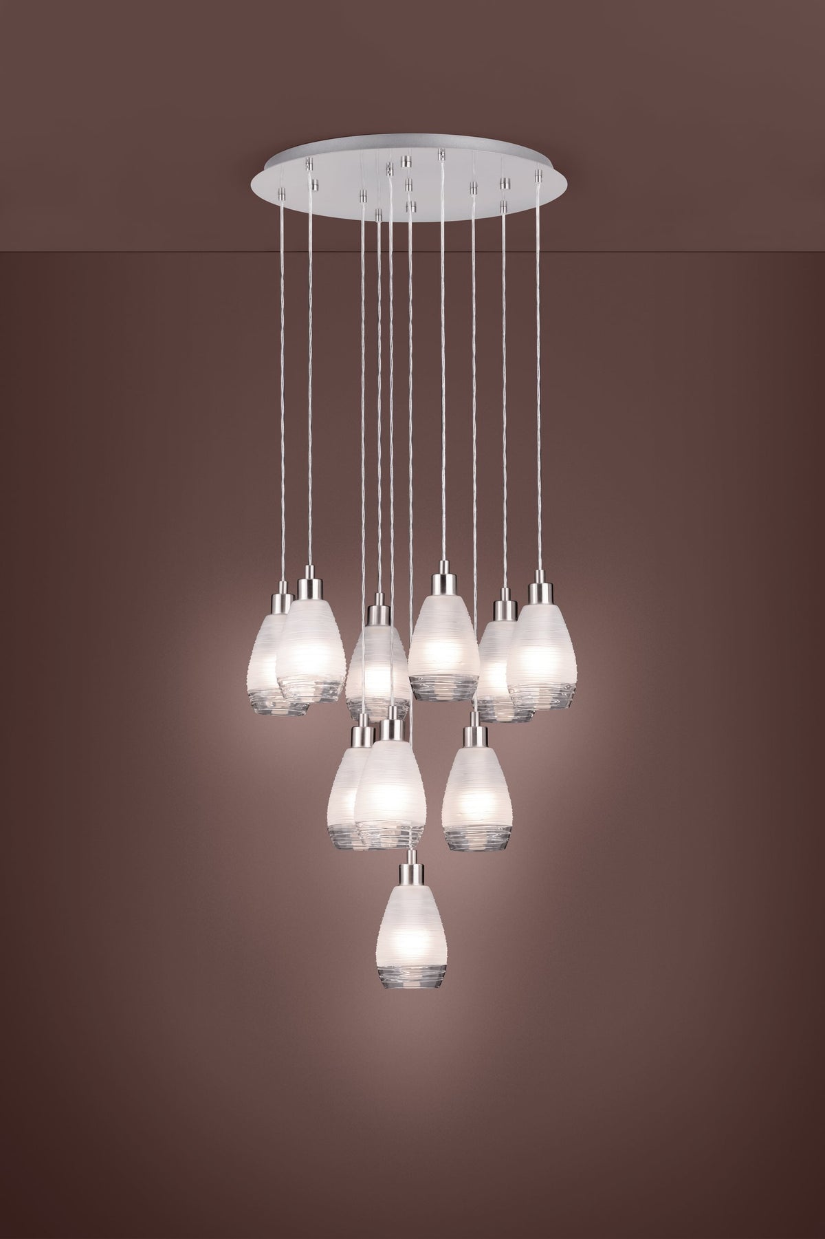 Vue en situation du luminaire allumé, abat-jours diffusant une lumière chaude sur fond brun