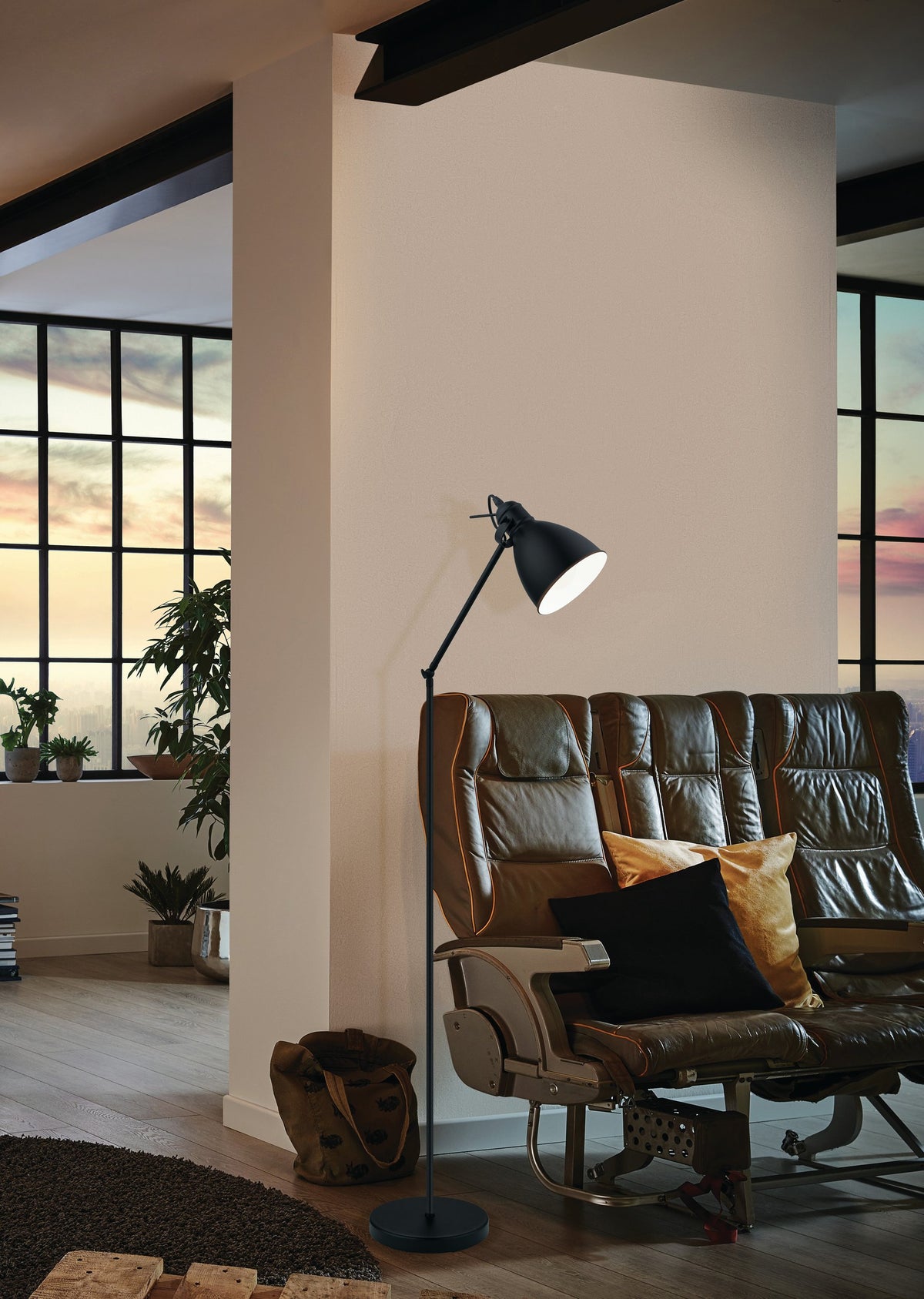 Lampadaire à côté d'un fauteuil en cuir, baies vitrées au coucher du soleil