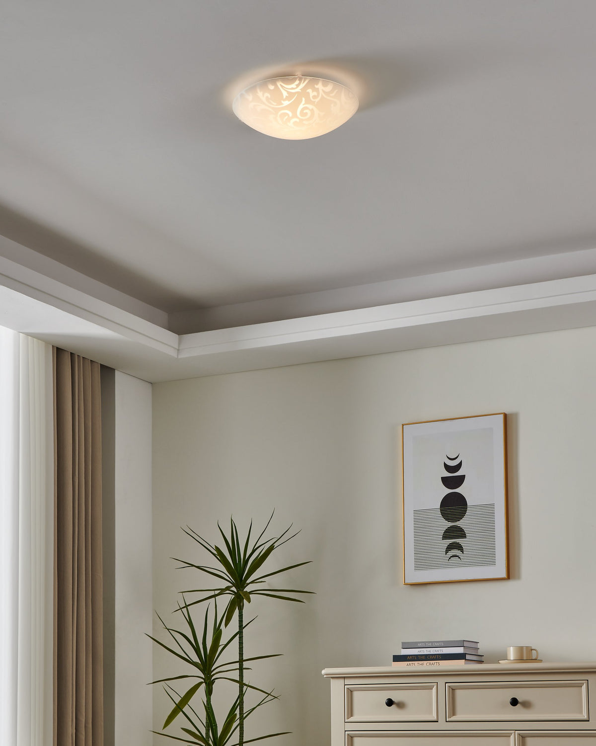 Luminaire allumé au plafond dans un intérieur clair avec plante et cadre