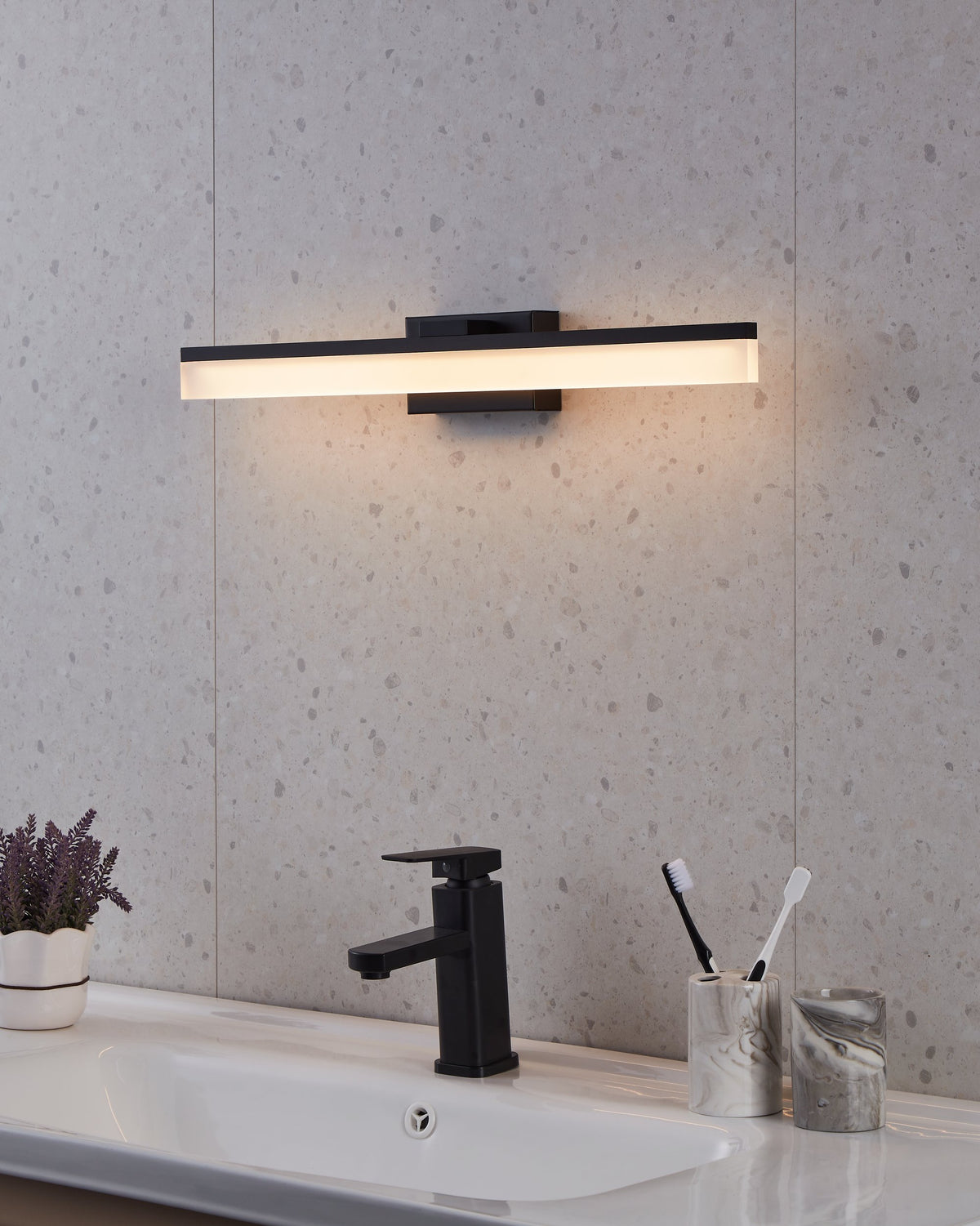 Luminaire allumé au-dessus d'un lavabo moderne dans une salle de bain.