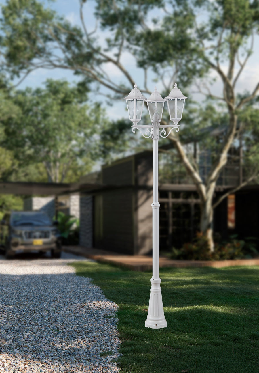 Mise en situation de jour dans un jardin, lampadaire blanc éteint devant une maison