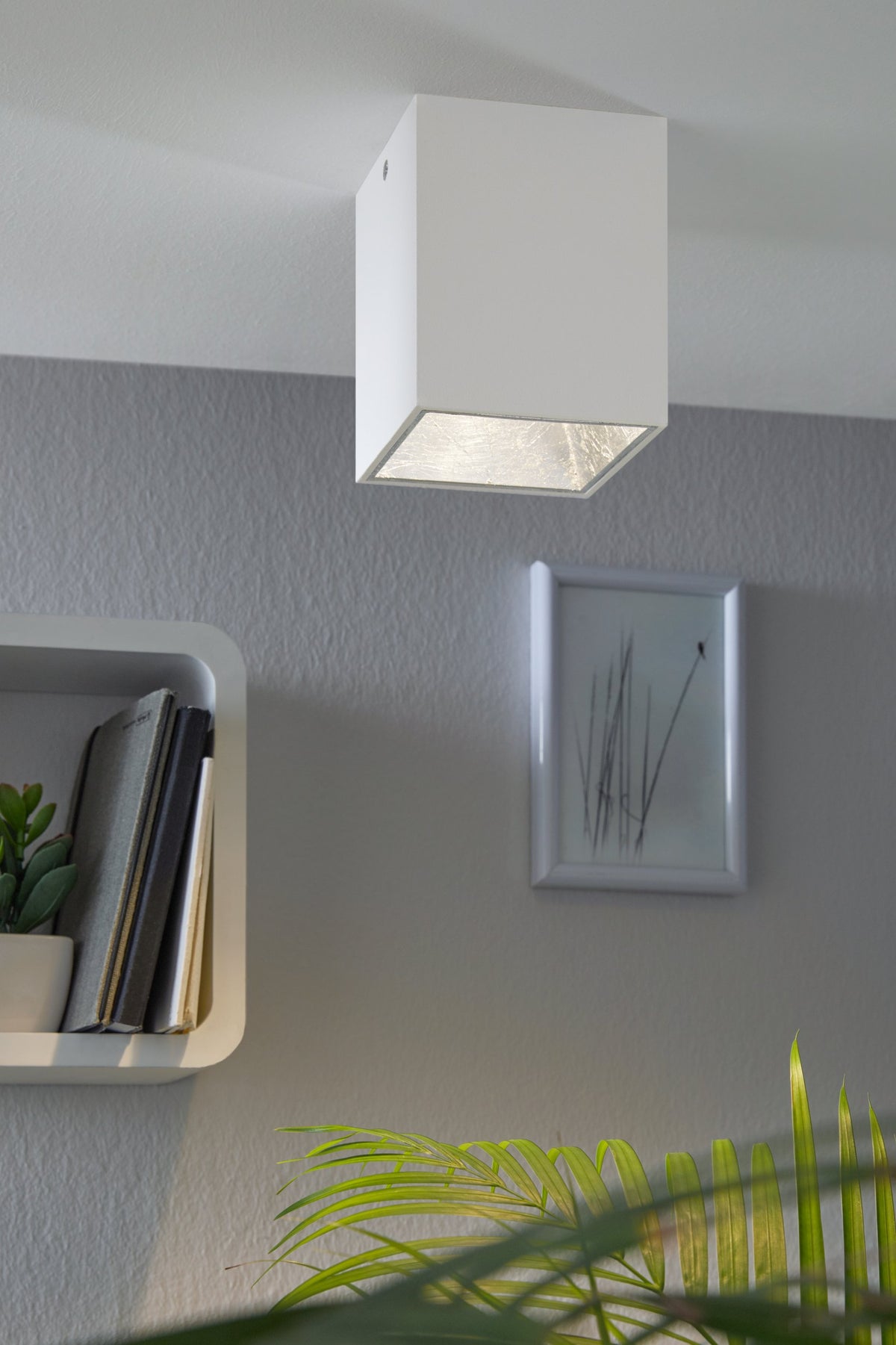 Plafonnier blanc installé au plafond dans un intérieur gris avec étagère