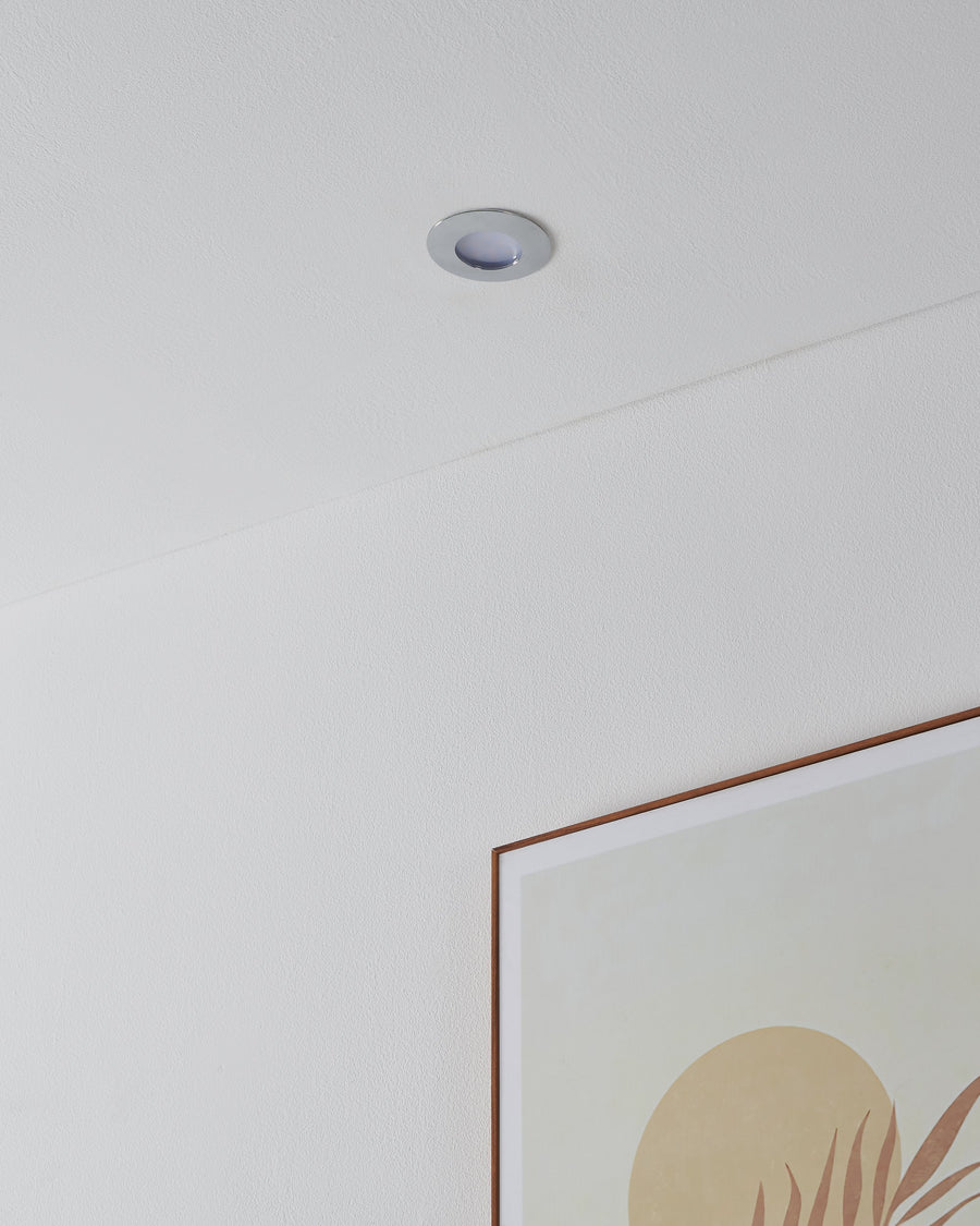 Spot encastré éteint intégré au plafond, discret au-dessus d'un tableau