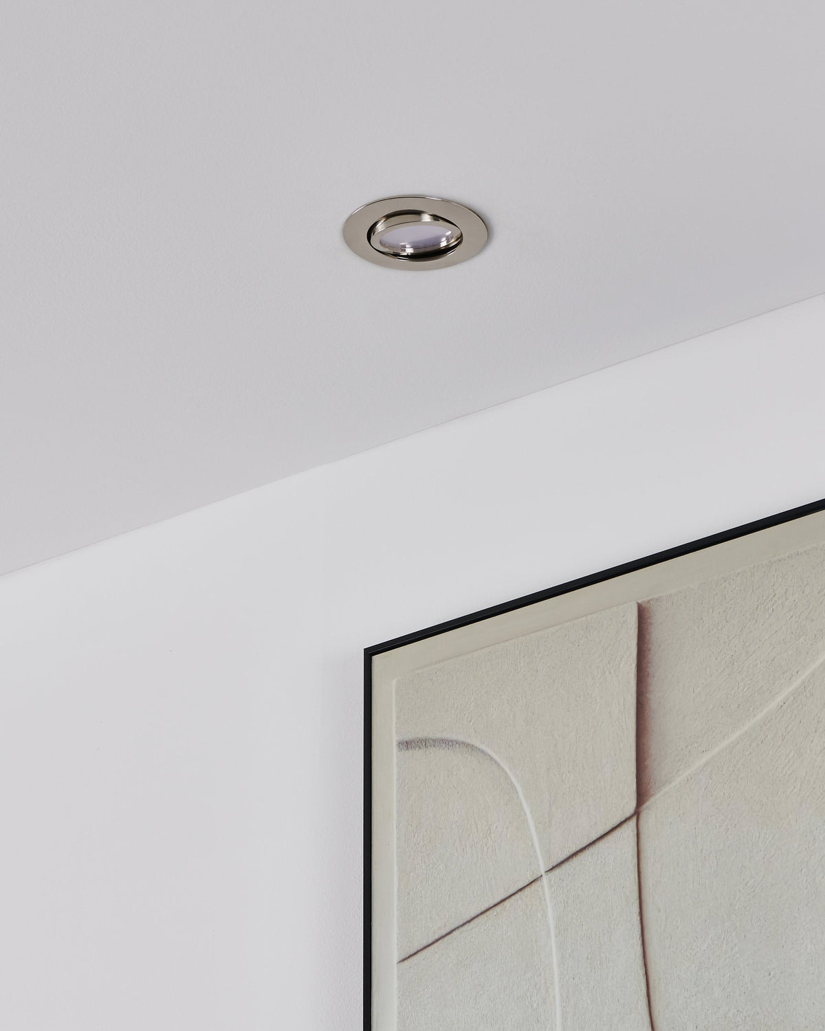 Vue de plafond avec spot éteint, anneau chromé brillant et cadre textile clair