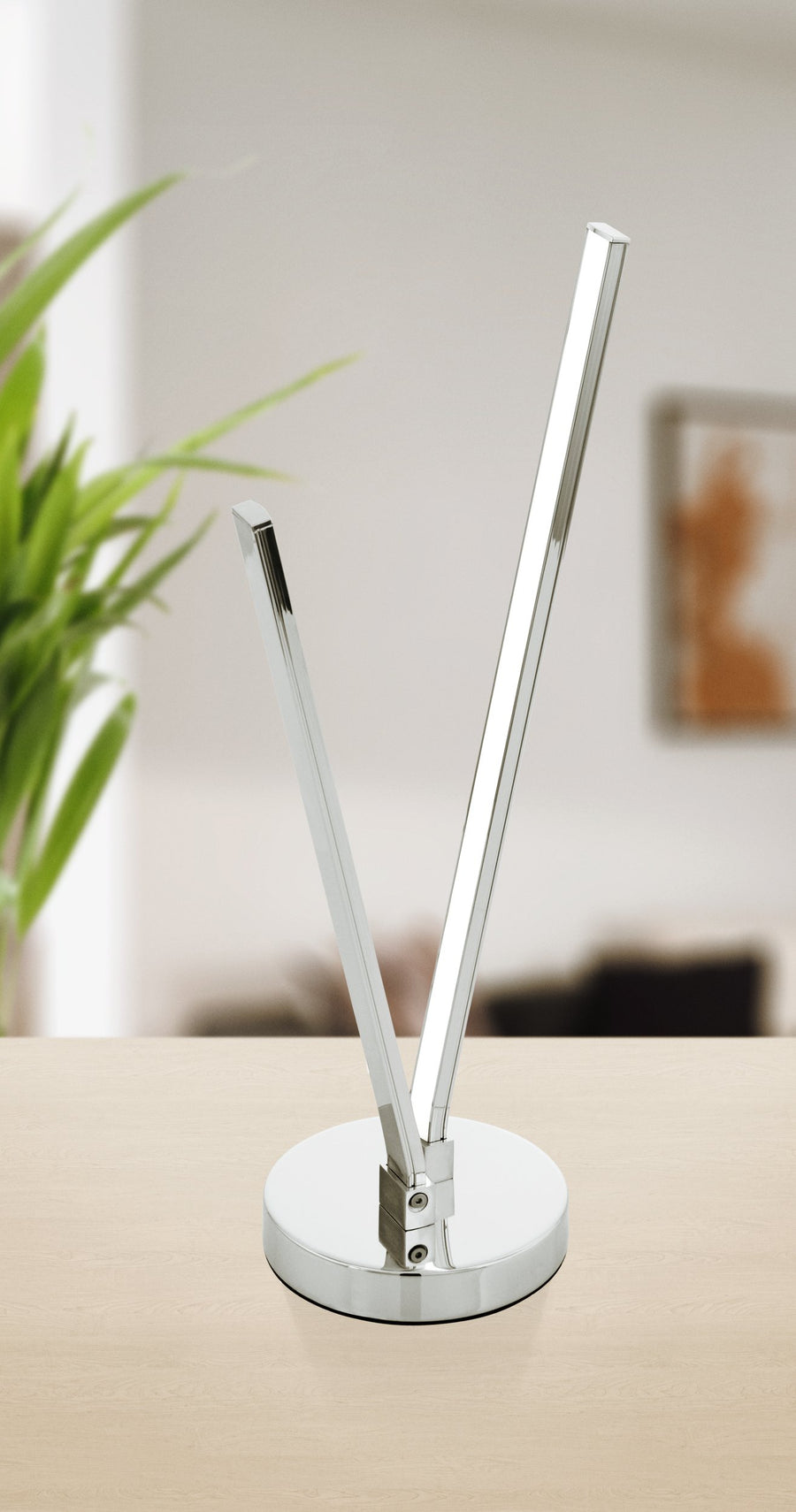 Lampe chromée posée sur une table en bois clair, arrière-plan flou