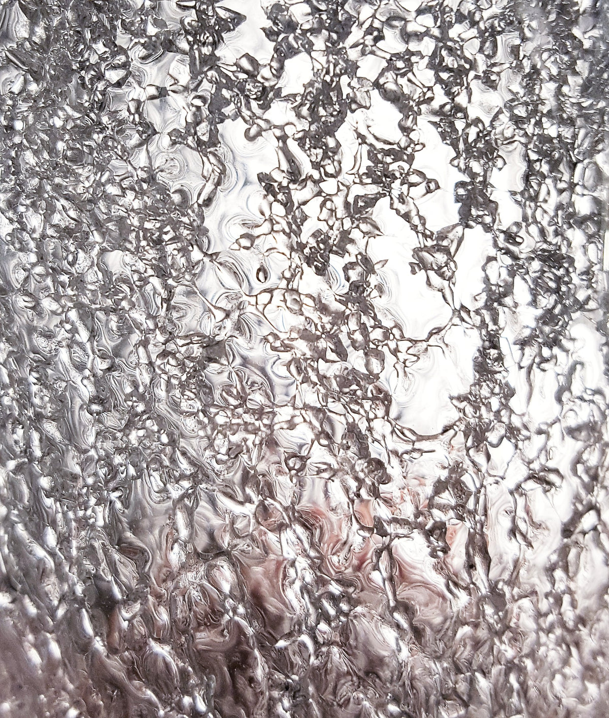 Texture du verre éclaté translucide, reflets argentés et veines ondulées en gros plan