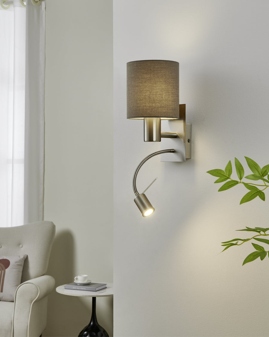 Applique murale installée dans un salon clair avec fauteuil et plante verte.