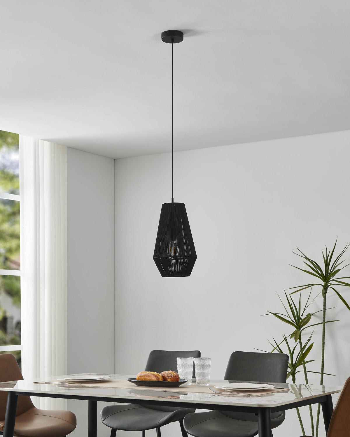 Mise en ambiance avec suspension allumée, table en marbre et plantes vertes