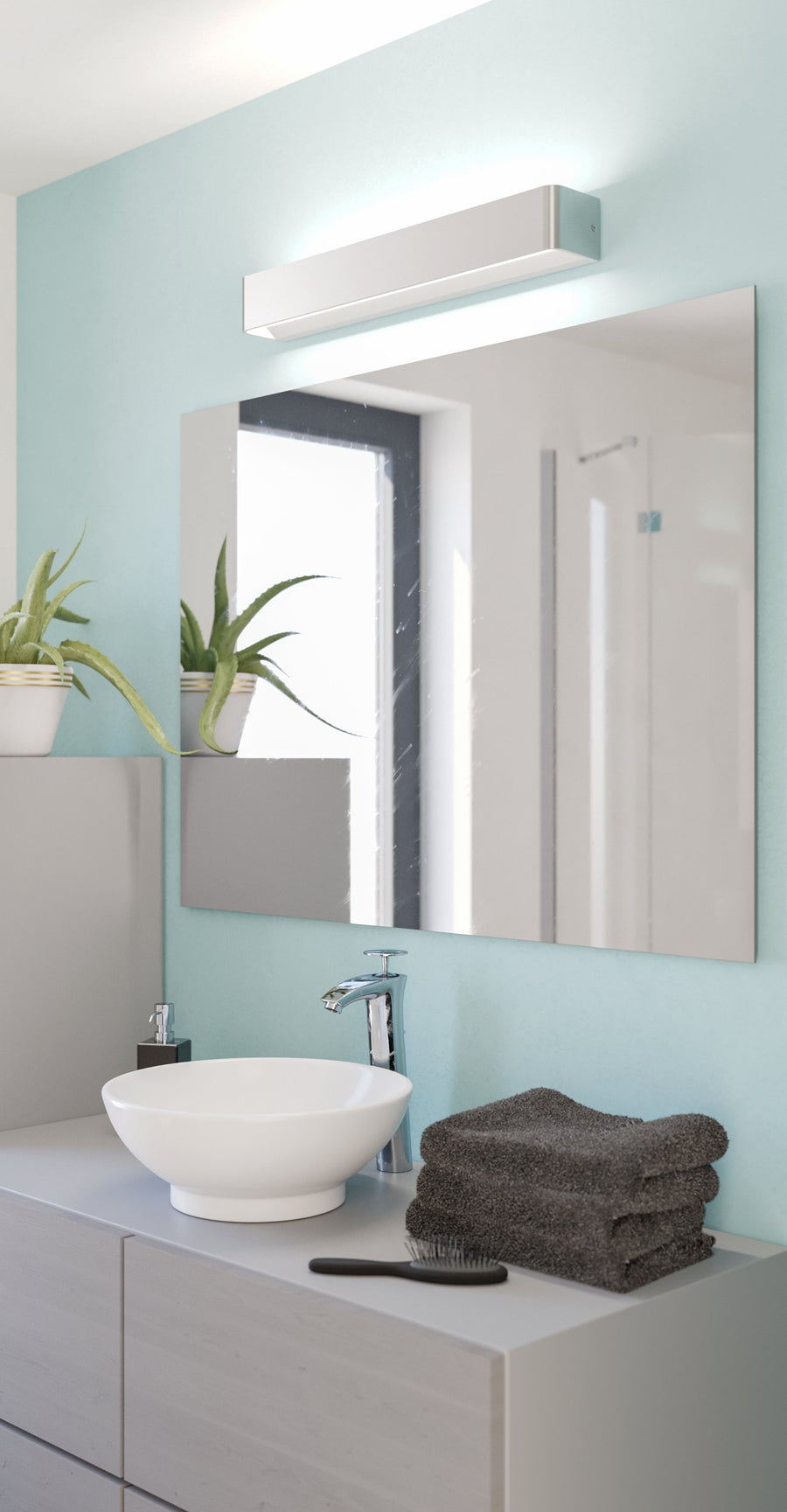 Applique allumée fixée au-dessus d'un miroir dans une salle de bain bleu clair