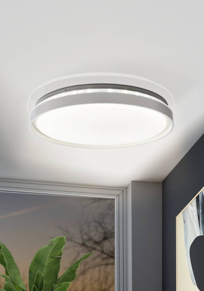 Plafonnier allumé au plafond d'un salon, près d'une fenêtre et d'une plante