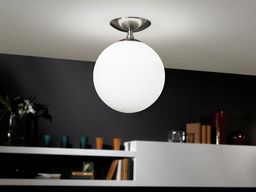 Plafonnier allumé dans un intérieur sombre, au-dessus d'une étagère blanche