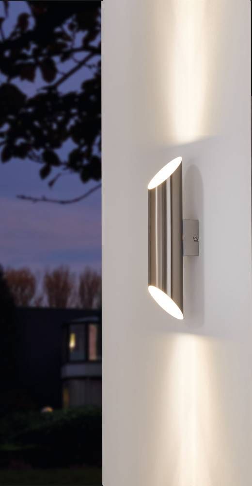 Applique murale installée sur un mur blanc, éclairant vers le haut et le bas la nuit.