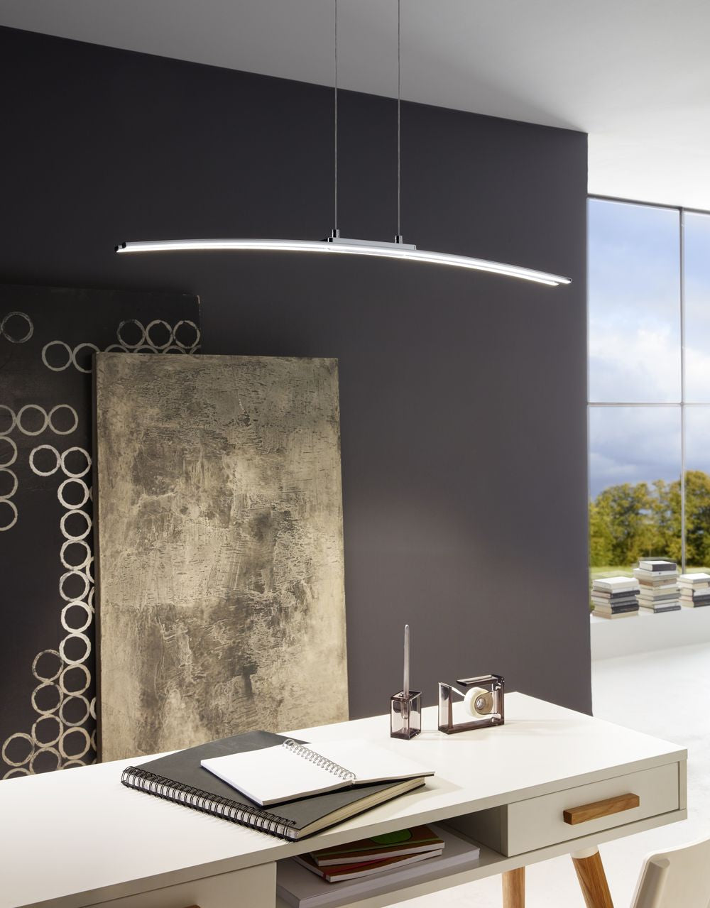 Mise en ambiance du luminaire au-dessus d'un bureau avec carnets et décoration murale