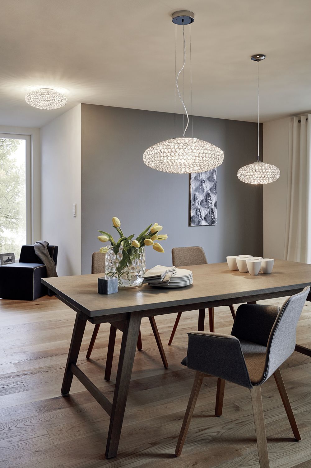 Mise en ambiance salle à manger, trois suspensions allumées au-dessus d'une table en bois