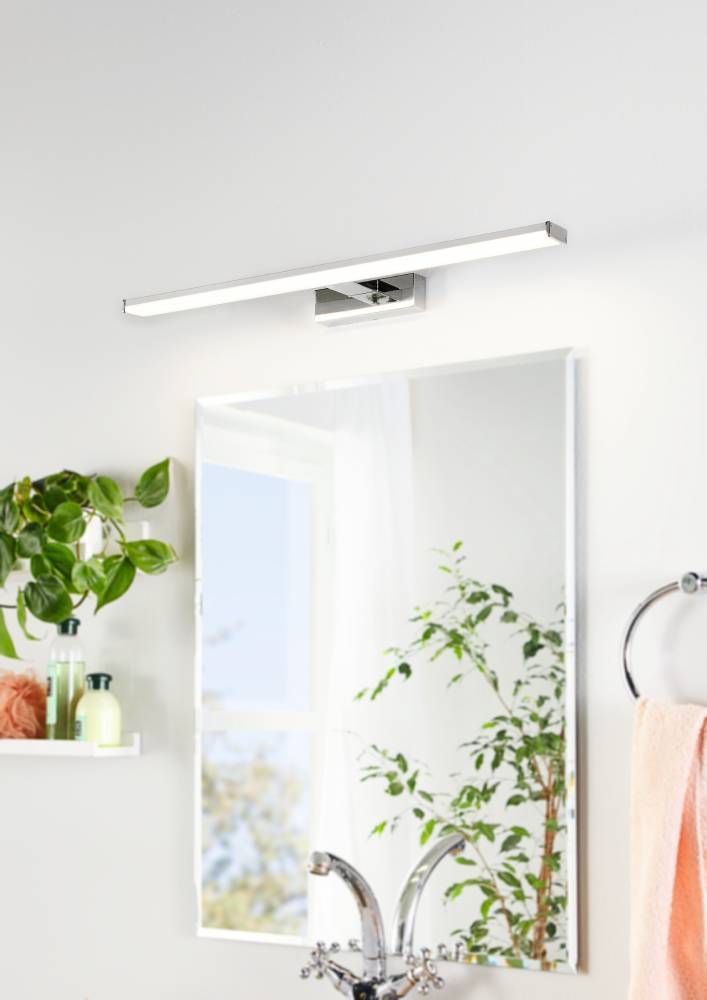 Mise en ambiance salle de bain, applique allumée au-dessus d'un miroir avec plantes