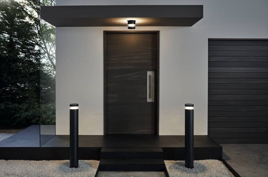 Mise en situation extérieure de l'applique noire au-dessus d'une porte avec bornes