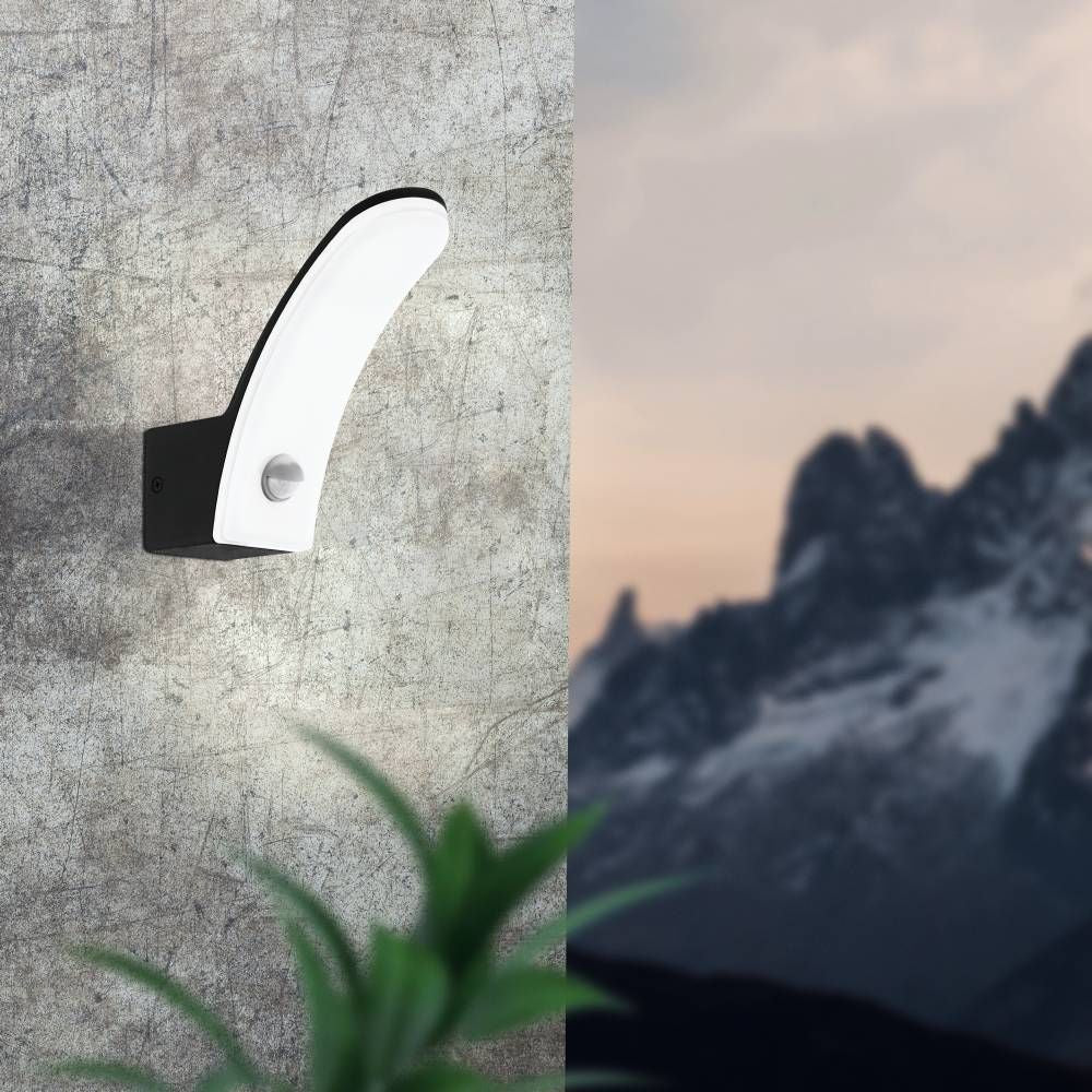 Mise en situation de l'applique murale noire et blanche sur un mur béton, montagne en arrière-plan
