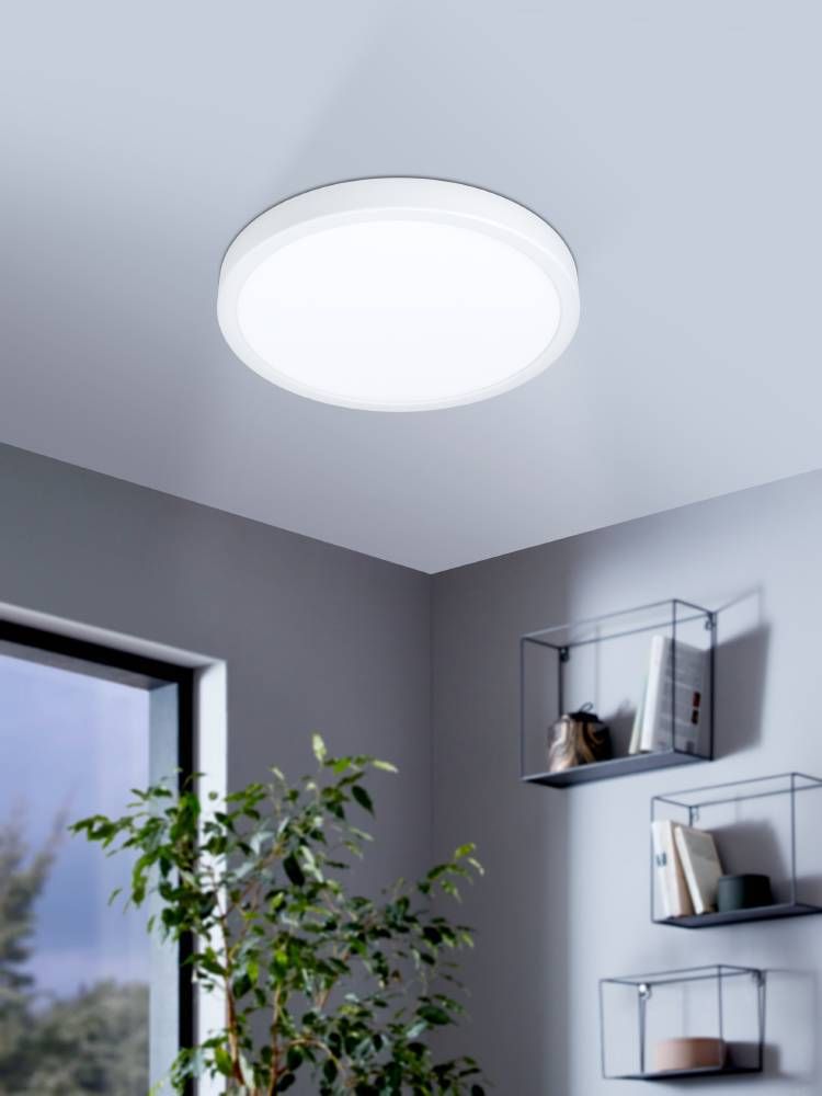 Plafonnier blanc fixé au plafond d'un salon gris avec plante et étagères