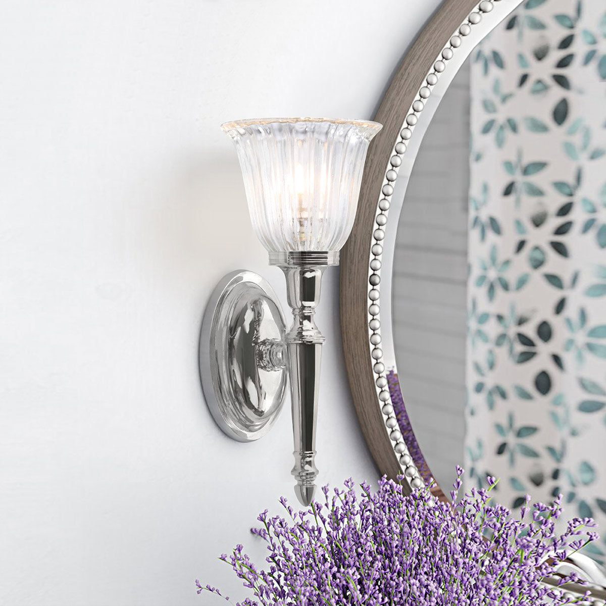 Applique allumée fixée au mur près d'un miroir rond et de lavande